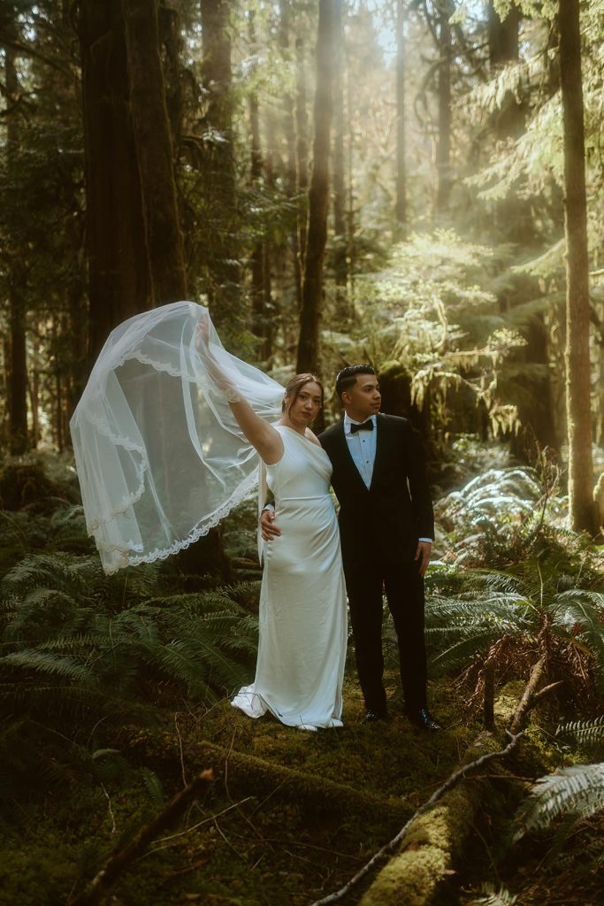 a groom and a bride standing in a lush forest