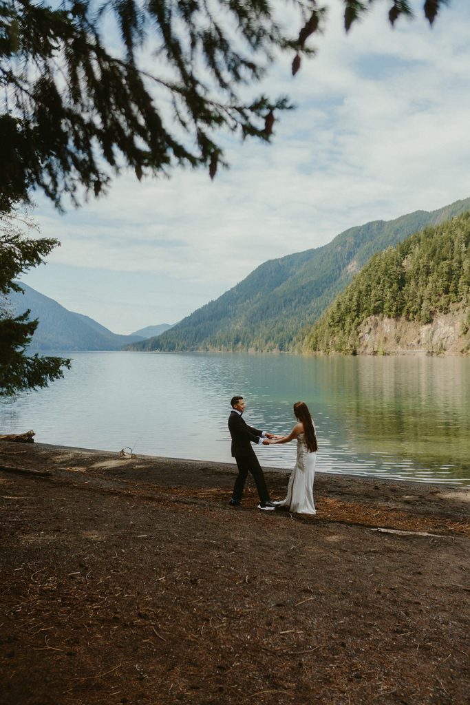 a groom and a bride walking along Lake Crescent during their elopement