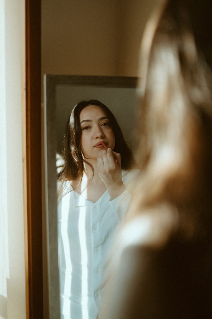 reflection of a woman getting make up in a mirror